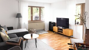A living room with a sofa, a coffee table, a television, and a foosball table. - Vacation apartment Panoramablick in Todtmoos (Todtmoos)