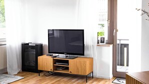 A modern living room with a flat-screen TV on a wooden stand, a fireplace, and a balcony with a door. - Vacation apartment Panoramablick in Todtmoos (Todtmoos)