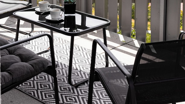A balcony with a table and chairs, a potted plant, and a view of a forested area. - Vacation apartment Panoramablick in Todtmoos (Todtmoos)