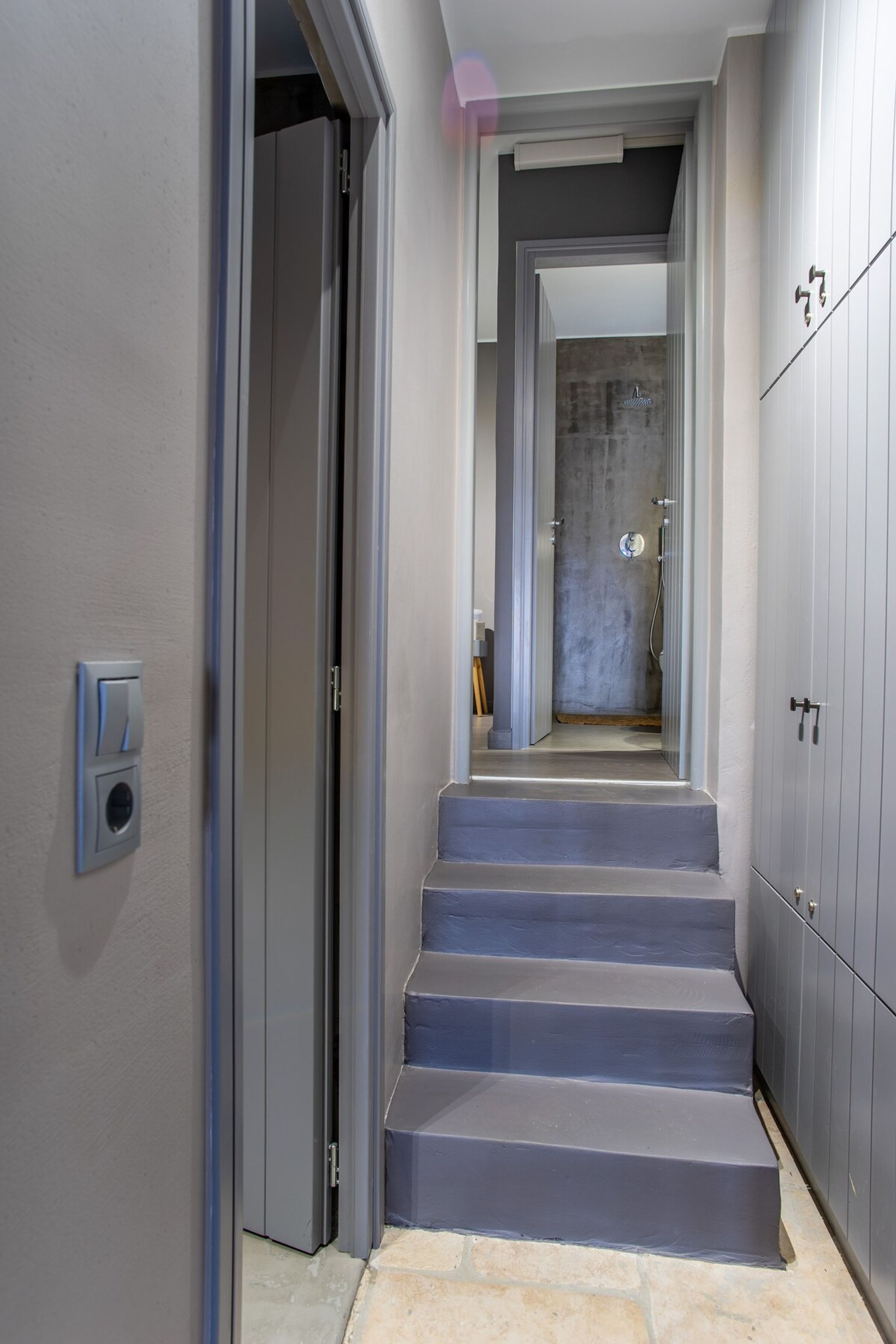 A hallway with a staircase leading to a bathroom.