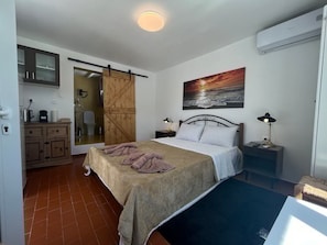 A bedroom with a bed, a painting, a desk, and a wardrobe. - Stephany s Skyline Studio (Paros)