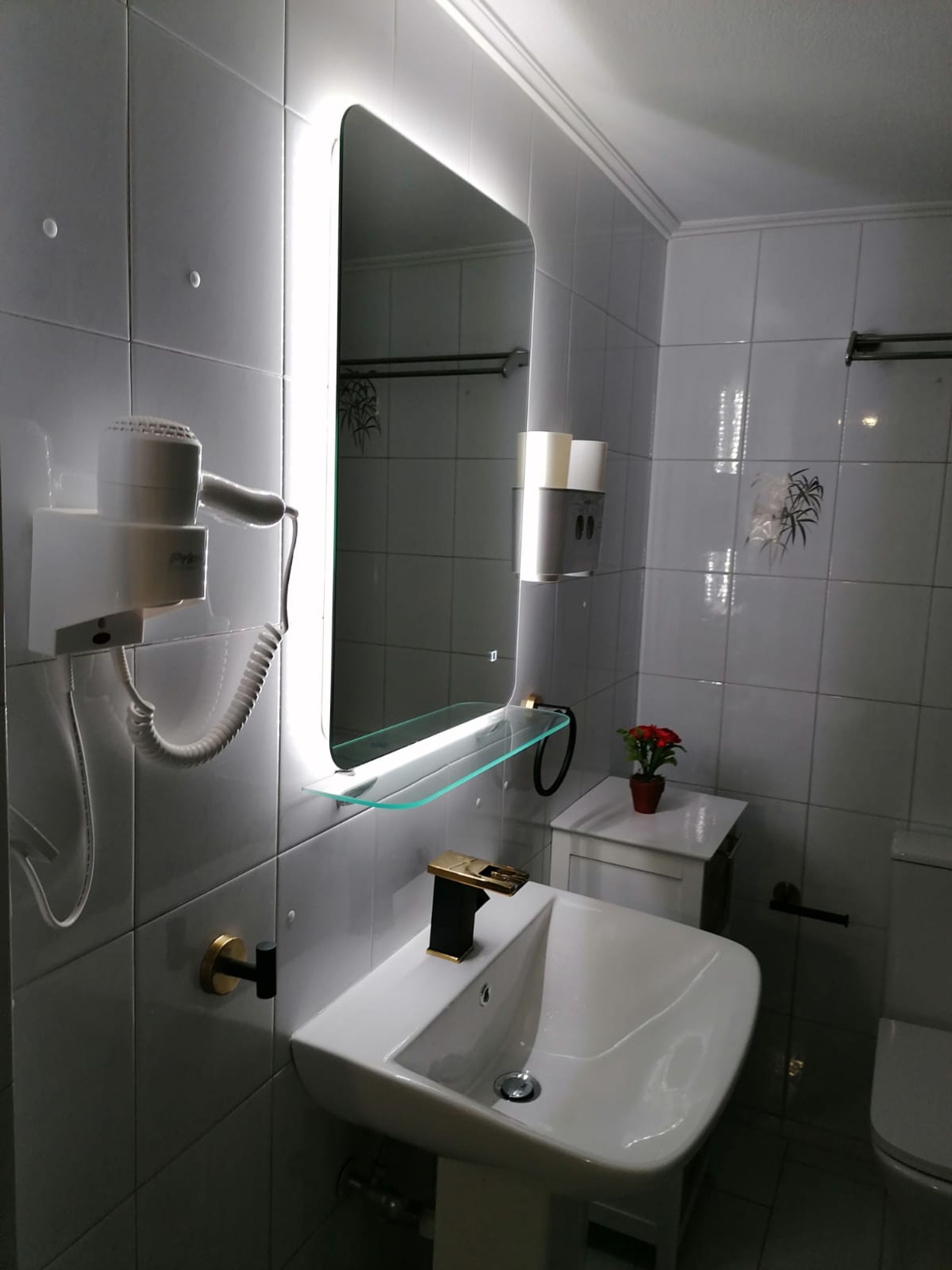 A modern bathroom with a glass shelf, a sink, a mirror, and a hairdryer.