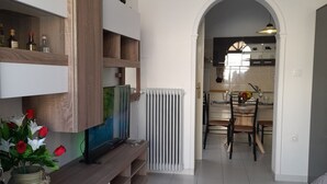 Una sala de estar moderna con televisor, estanterías de madera y un jarrón de flores.