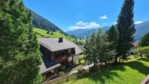 A mountain house with a sloped roof, surrounded by lush greenery and a clear blue sky. - Cozy Apartment with mountain view (Bad Kleinkirchheim)