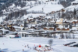 Un pueblo cubierto de nieve con casas de madera tradicionales, una iglesia y una pista de esquí.