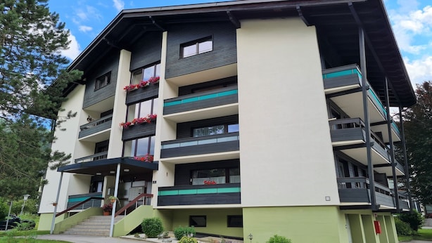 A multi-story building with balconies, a staircase, and a green entrance area.