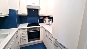 A compact kitchen with white cabinets, a built-in microwave, a toaster, and a sink.