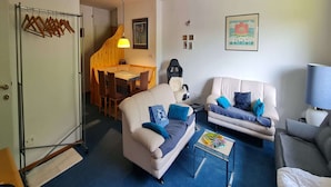 A living room with two sofas, a coffee table, and a dining area with a table and chairs.