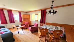 Een gezellige kamer met een bank, twee stoelen, een tafel en een houten kast.