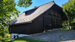 Een rustiek houten gebouw met een schuin dak en een entree van stenen plavuizen.