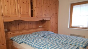 Una cama litera de madera con colcha a cuadros azul y blanca.