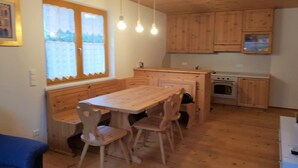 Una cocina de madera con una mesa de comedor y sillas, una ventana con cortinas y armarios de madera.