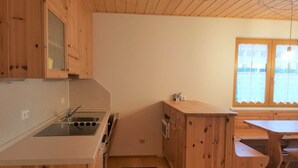 Una cocina compacta con armarios de madera, estufa integrada y microondas. Hay una ventana con vistas al exterior.