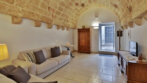 A cozy living room with a stone ceiling, a sofa, a cabinet, and a television. - Relax Star House. An oasis of peace in the heart of Salento (Presicce-Acquarica)