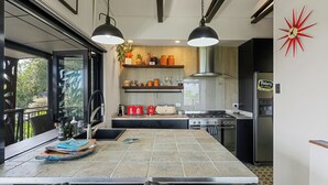 Une cuisine moderne dotée d’un grand îlot central, d’appareils électroménagers intégrés et offrant une vue sur l’extérieur.