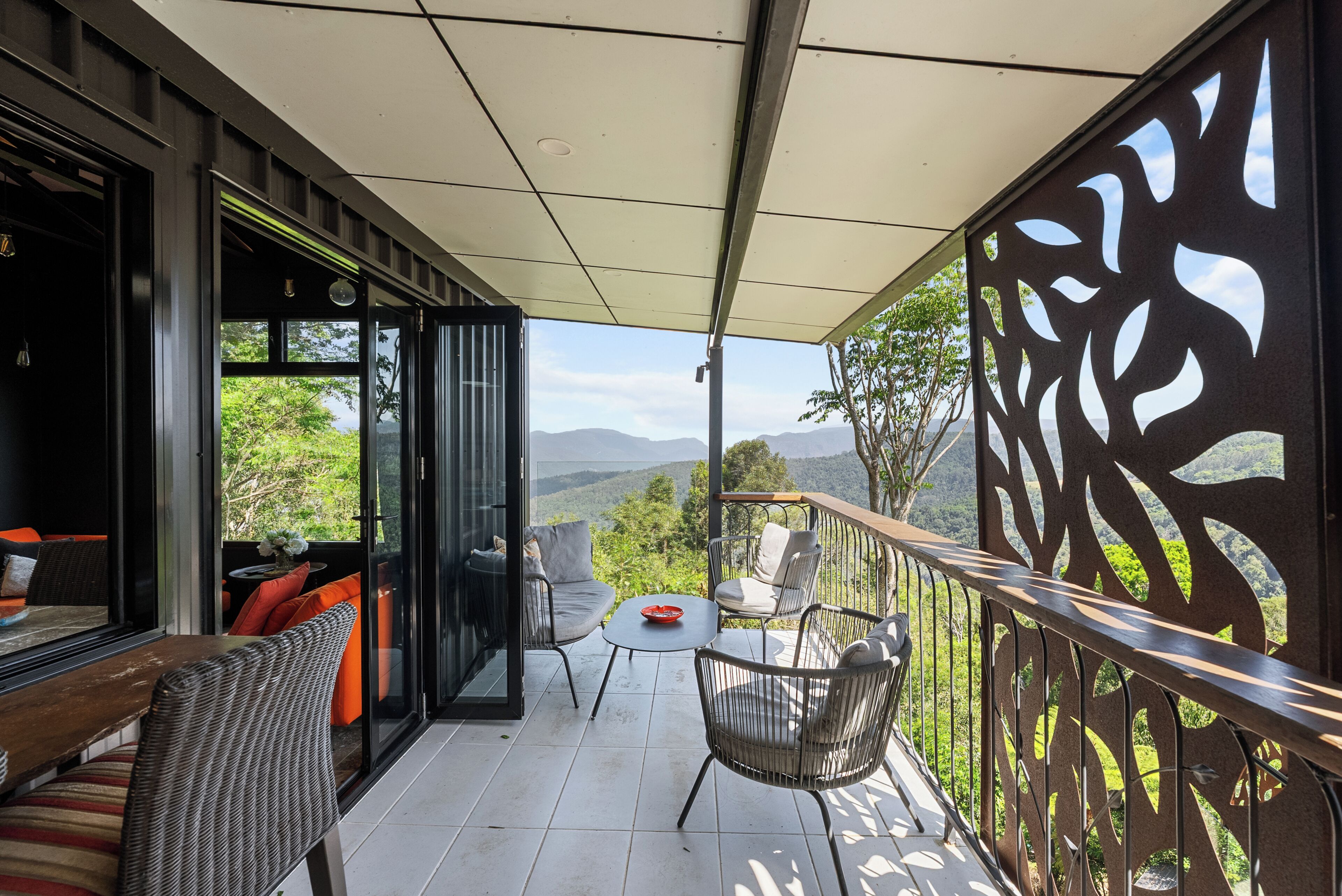 A balcony with wicker furniture, a glass door, and a view of the mountains.