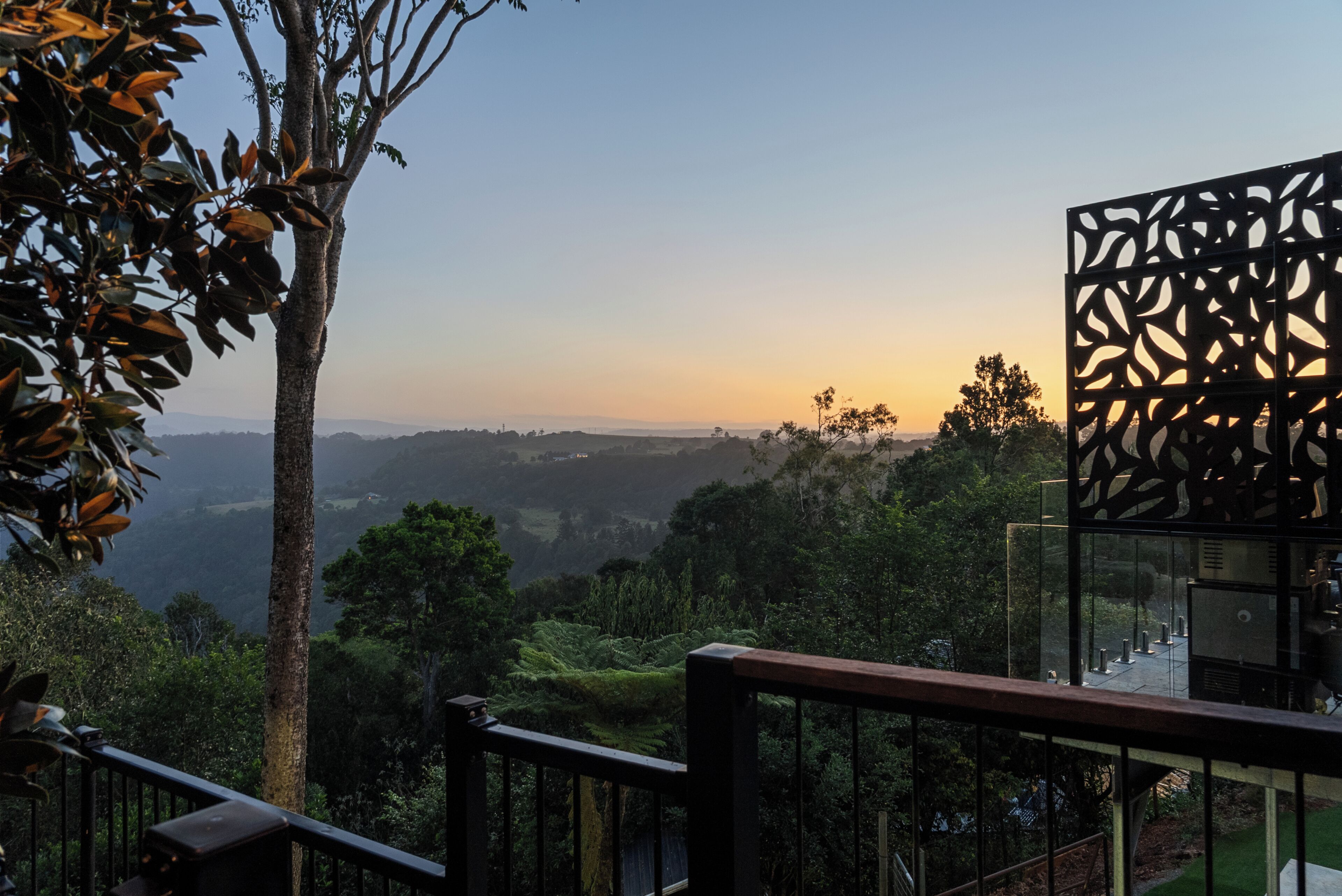 A view from a balcony overlooking a lush landscape with a clear sky.