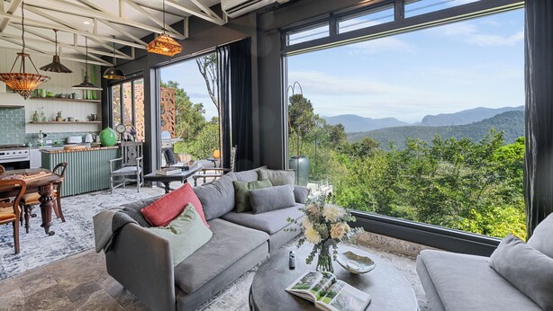 A modern living room with a large window offering a scenic view of mountains.