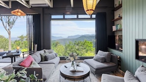 A modern living room with a large window offering a mountain view, a sofa set, a coffee table, and decorative lighting.