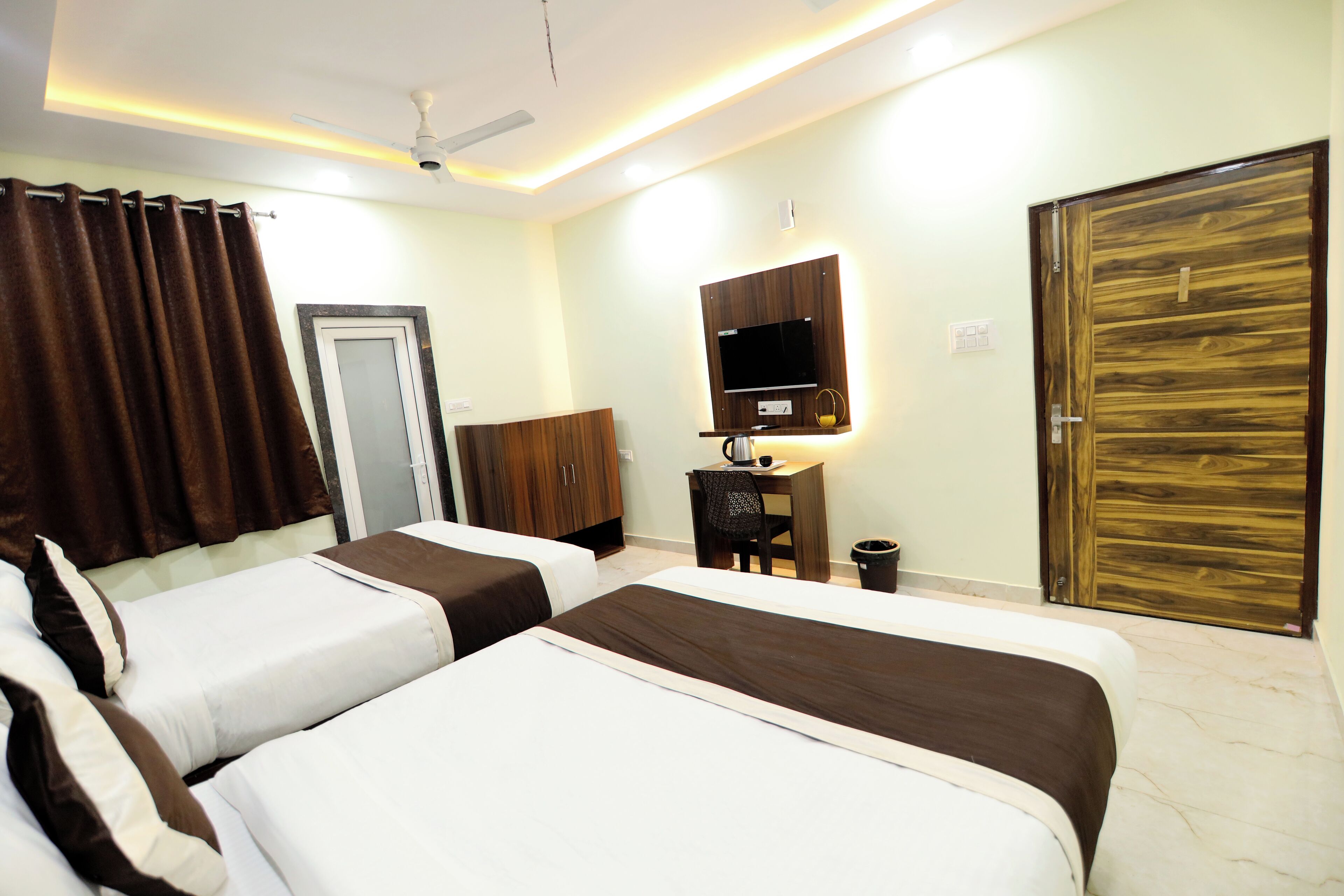 A hotel room with two beds, a desk, a chair, a television, and a wardrobe.