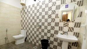 Een badkamer met een betegelde muur met een patroon, een toilet, een wastafel en een spiegel.