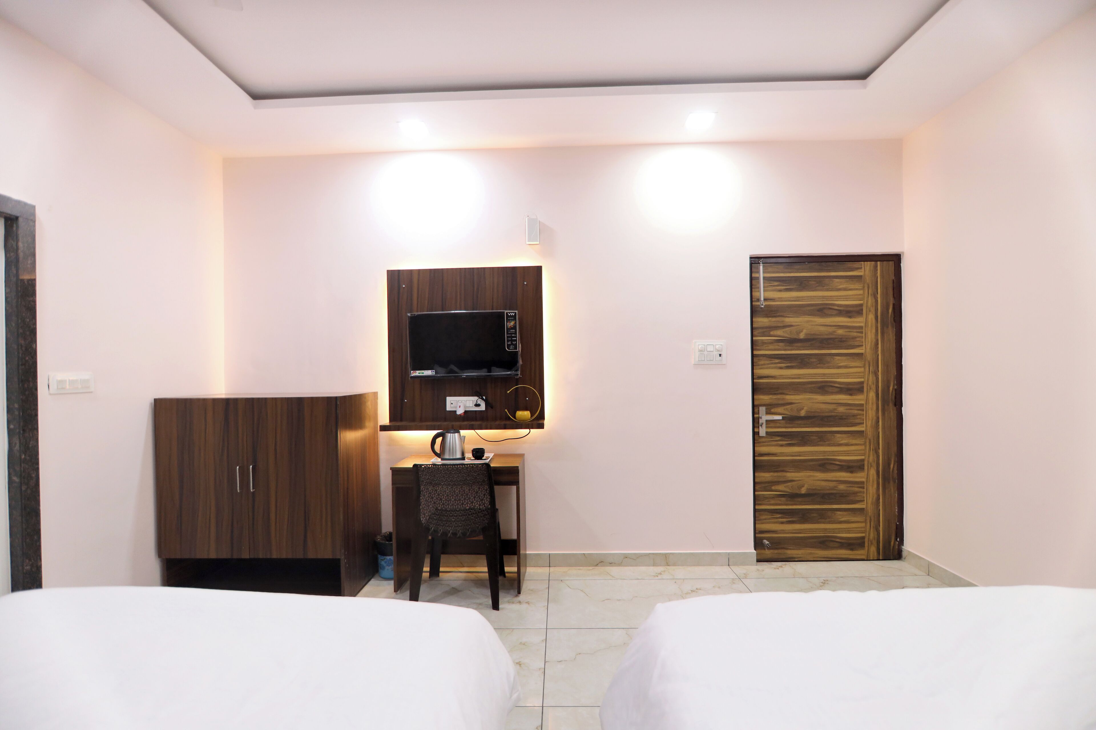 A hotel room with two beds, a desk with a chair, a microwave, and a wooden door.