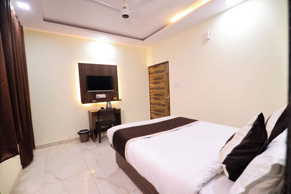 Ein Hotelzimmer mit Bett, Schreibtisch, Stuhl, Fernseher und Deckenventilator.