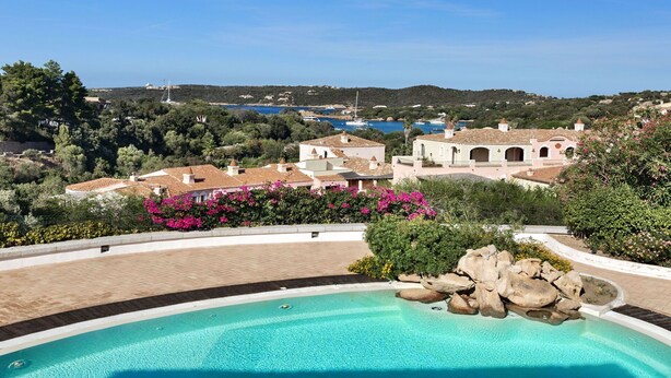 A pool area with a clear view of a coastal town, featuring traditional architecture and a view of the sea. - Cosy apartment for 4 people with WIFI, A/C, pool and TV (Porto Cervo)