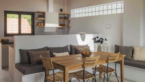 Eine moderne Küche mit einem Holztisch, Korbstühlen und einer eingebauten Bank mit Kissen.
