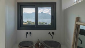 Ein Badezimmer mit zwei Steinsinks, einem Fenster mit Blick auf Berge und einen See sowie einem Holzhandtuchhalter.