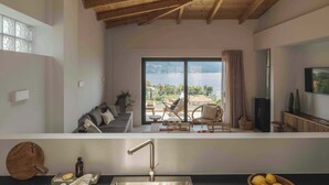 Eine moderne Küche mit einem großen Fenster, Holzbalken an der Decke und Blick auf das Meer.