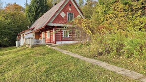 Une maison traditionnelle en bois, peinte en rouge, avec un toit en pente, un porche à l’avant et un chemin menant à l’entrée.