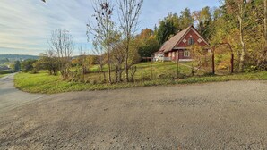 Une maison de campagne avec une allée en gravier, entourée d’arbres et sous un ciel dégagé.