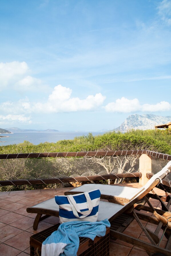 A terrace with a view of the sea, wooden lounge chairs, and a tiled floor. - Breeze of the Coast by Wonderful Italy (San Teodoro)