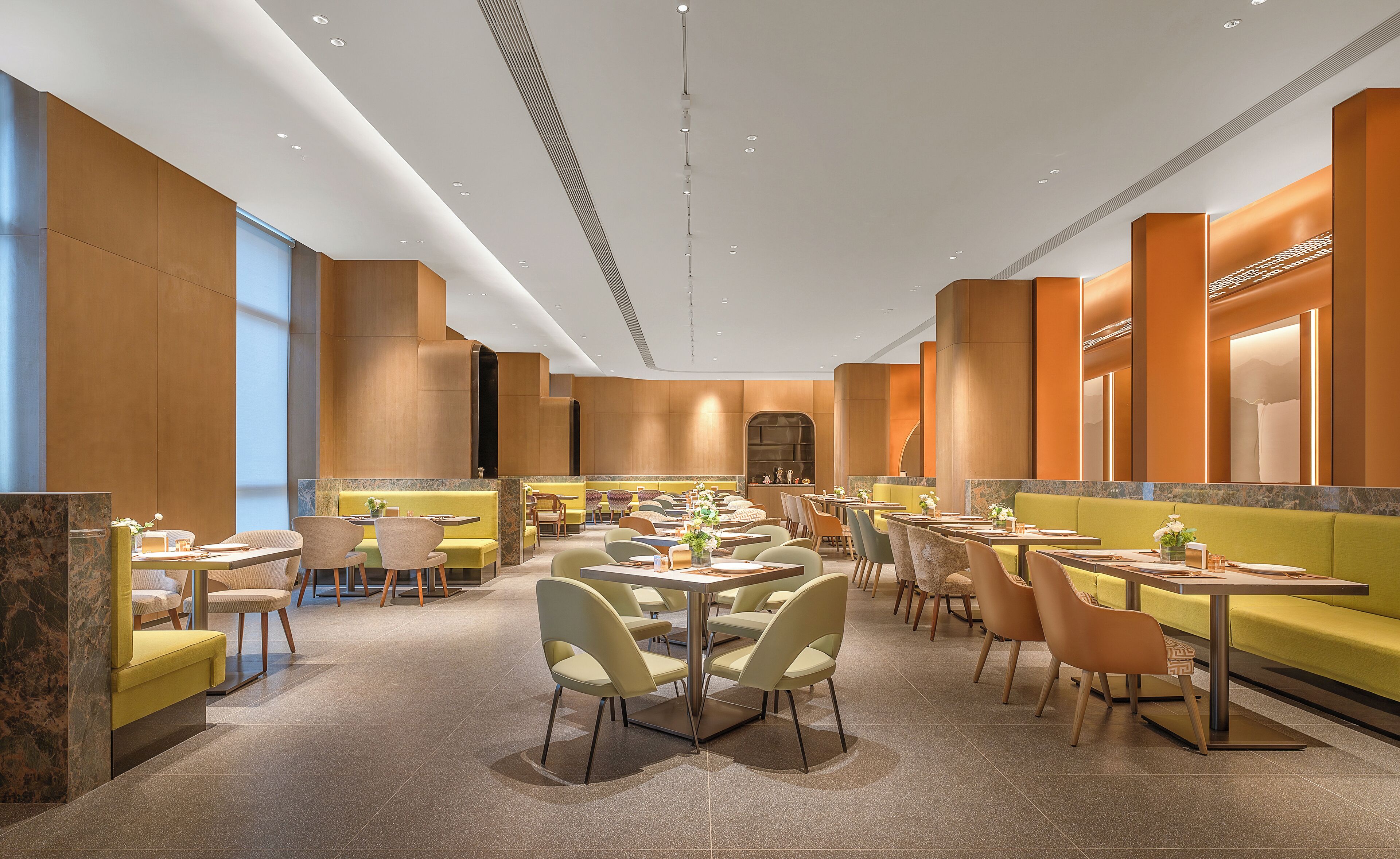 A modern restaurant with high ceilings, recessed lighting, and a mix of booth and table seating.