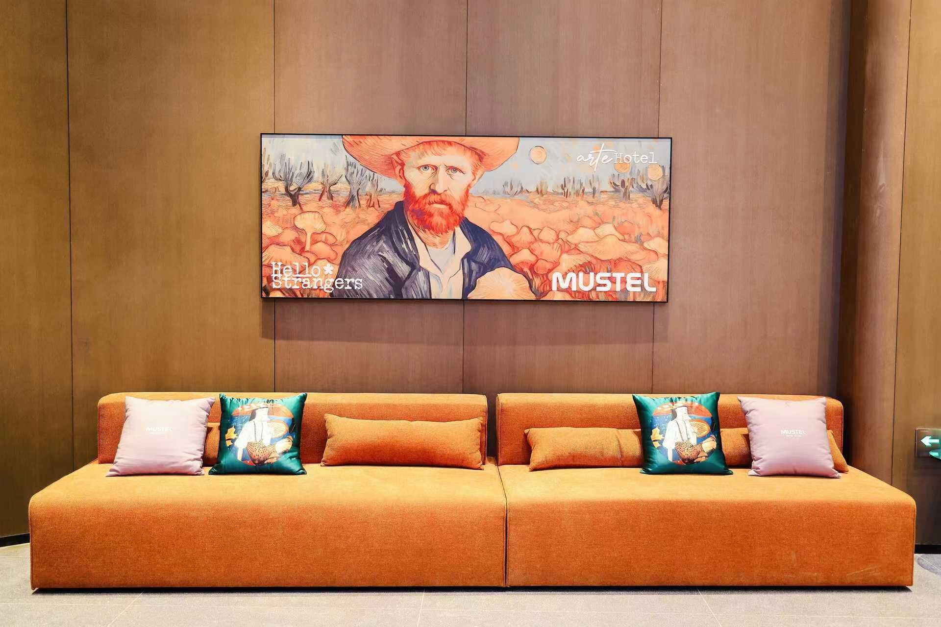Een kamer met een groot schilderij aan de muur, een wand van houten panelen en een bank met meerdere kussens.