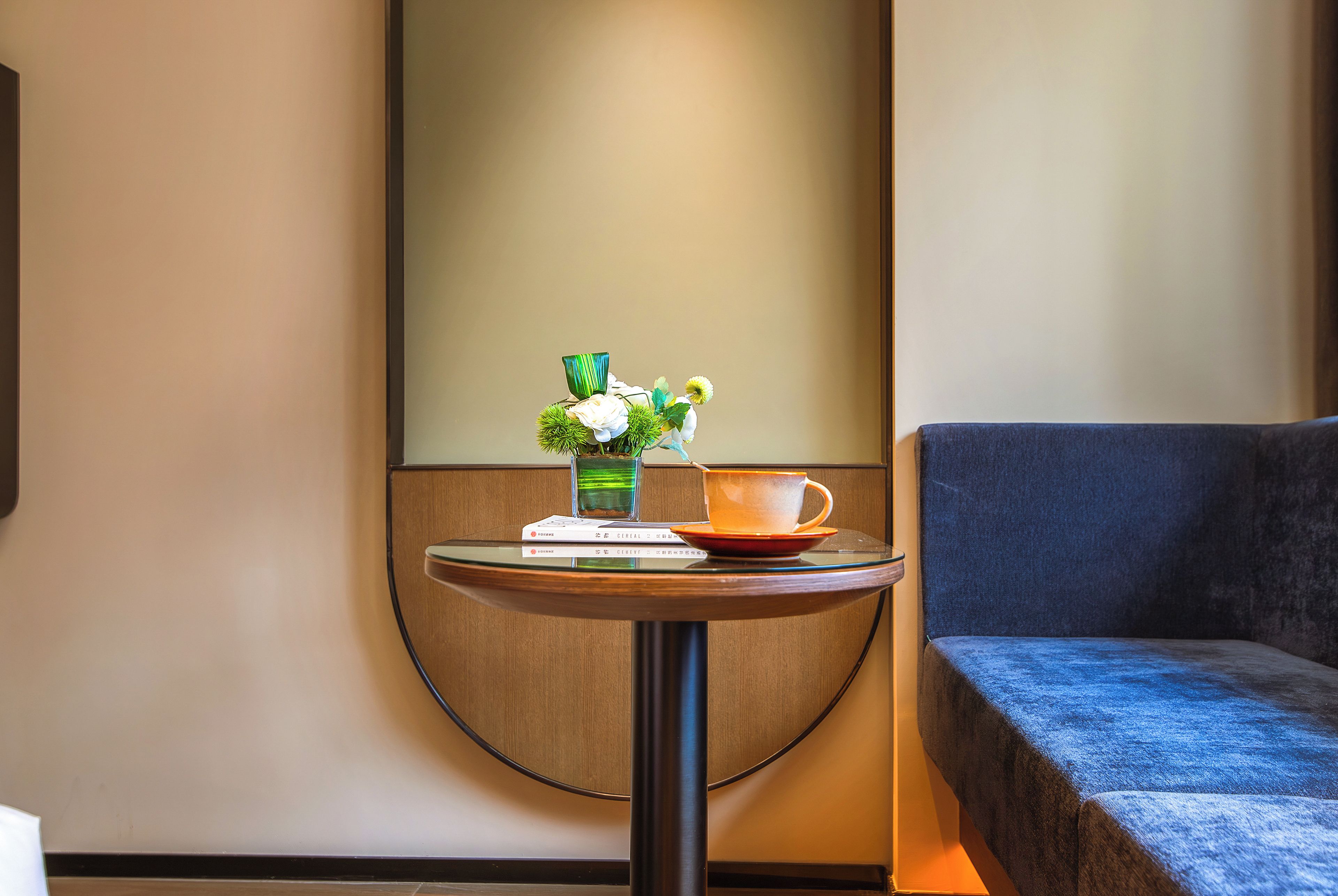 A small round table with a cup, saucer, and a vase with flowers.