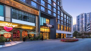 A modern hotel with a prominent 'MUSTEL' sign, large windows, and a well-lit entrance. - MUSTEL  ARTE  HOTEL  ZHENLIN  CHENGDU (Chengdu)