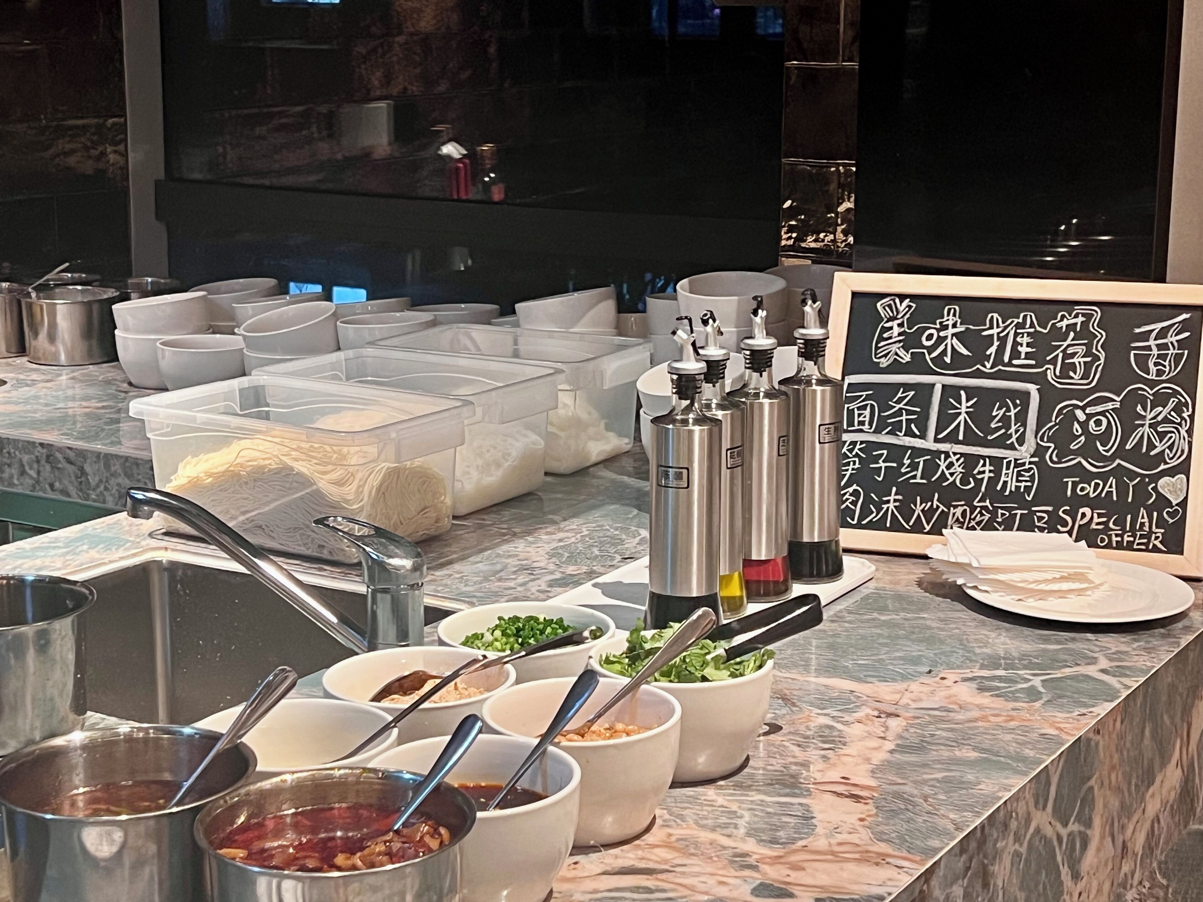 A buffet setup with various food containers and condiments.
