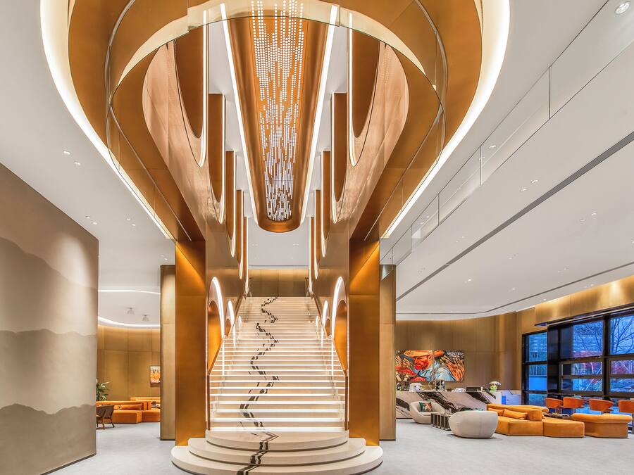 A modern interior with a central staircase, seating areas, and artwork on the walls.