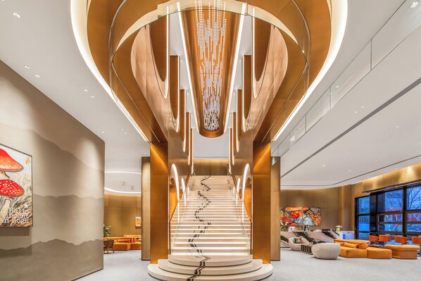 Un interior moderno con una escalera central, zonas de estar y obras de arte en las paredes.