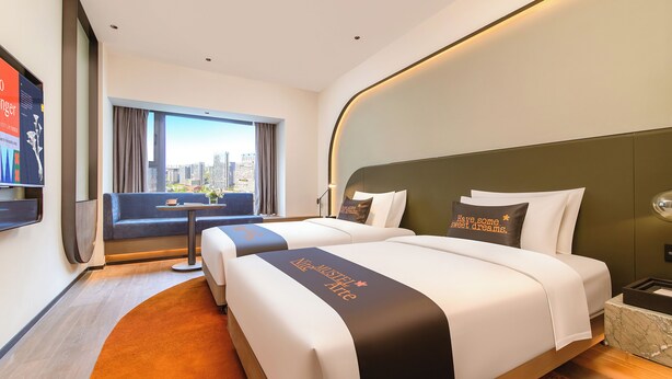 A hotel room with two beds, a city view, a desk, and a TV. - MUSTEL  ARTE  HOTEL  ZHENLIN  CHENGDU (Chengdu)