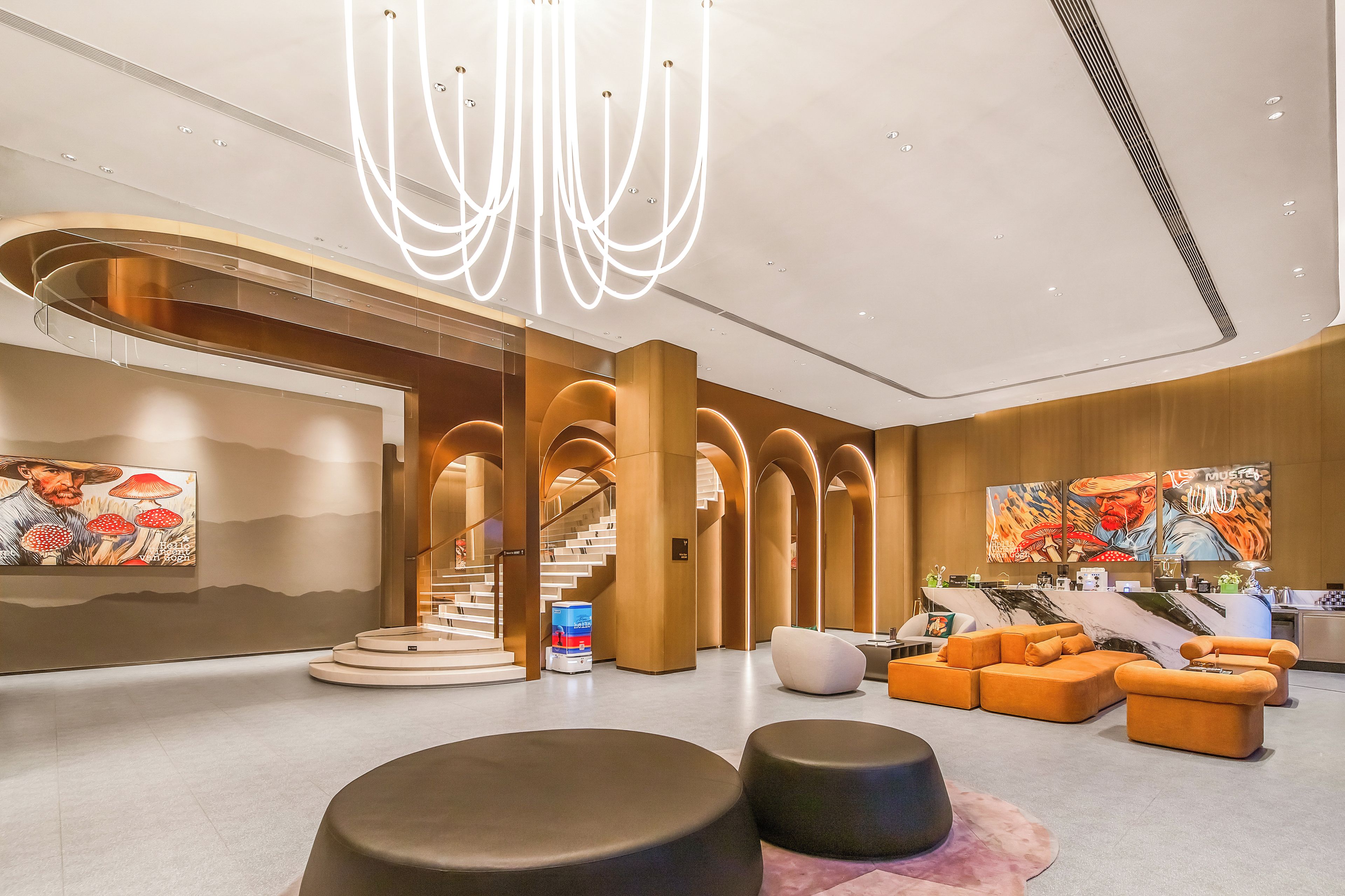 A modern lobby with a central staircase, seating areas, and artwork on the walls.
