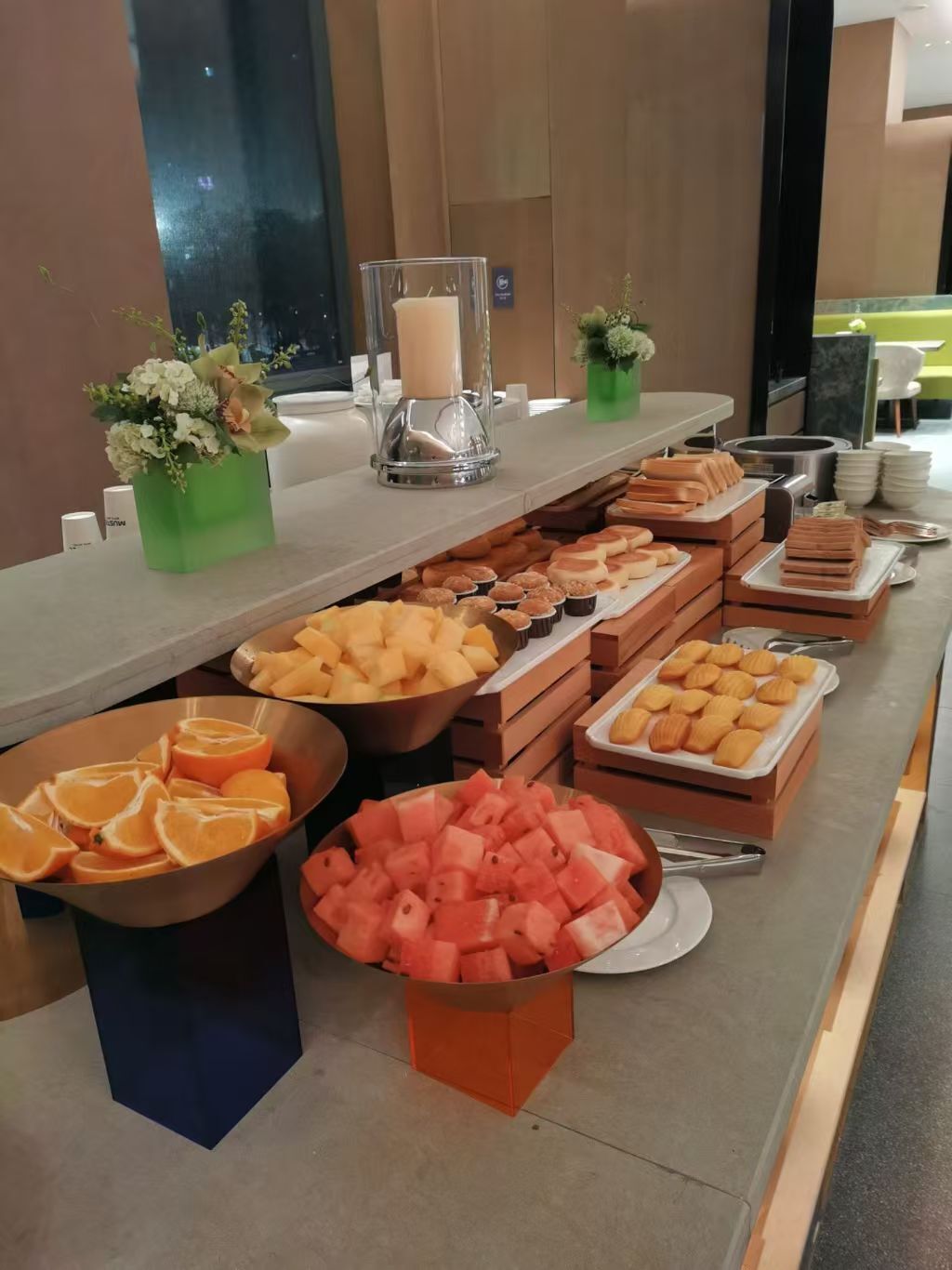 A buffet with various fruits, pastries, and a candle centerpiece.