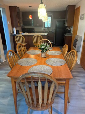 A dining area with a wooden table, six chairs, and a central plant. - Welcome To "Snowed Inn” - Walk On And Off The Slopes (McGaheysville)