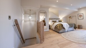 A bedroom with a bed, a round rug, and a wooden staircase. - The Dog Kennels, Leyburn (Leyburn)