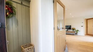 A modern interior with a wooden door, a wicker basket, a television on a wooden cabinet, and a plant. - The Dog Kennels, Leyburn (Leyburn)