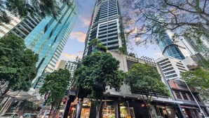 A tall building with a modern design, surrounded by trees and other buildings.