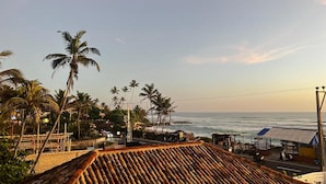 A coastal view with palm trees, a beach, and a road with vehicles. - Marshmallow Bay (Ahangama)