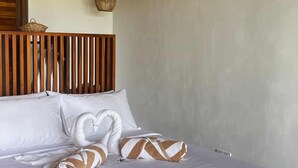 A neatly made bed with white linens and heart-shaped pillows, a woven light fixture, and a wooden headboard. - Marshmallow Bay (Ahangama)
